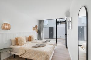 een witte slaapkamer met 2 bedden en een spiegel bij Chez Oti Puerto Rico in Puerto Rico de Gran Canaria +17 foto's