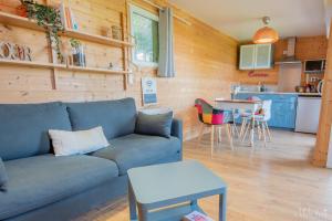 a living room with a blue couch and a kitchen at Chalet avec jacuzzi privatif in Fichous-Riumayou
