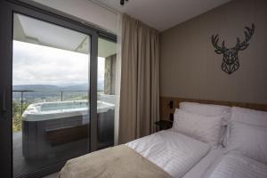 une chambre avec un lit et une vue sur une baignoire dans l'établissement Sky Hill Apartments Szklarska Poręba, à Szklarska Poręba