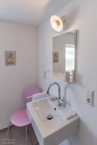 a bathroom with a sink and a mirror and two pinkchairs at Ferienhaus S`bunde Heisle in Blaufelden +30 photos
