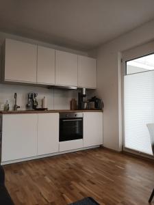 a kitchen with white cabinets and a wooden floor at Appartement Kärntner Seenland in Ledenitzen