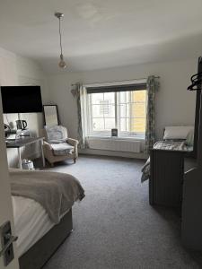 a bedroom with a bed and a window and a chair at Britannia inn in Sherborne