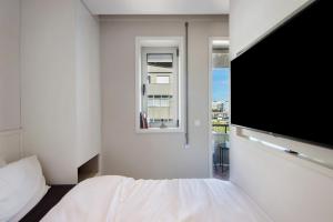 Un dormitorio con una cama y un televisor de pantalla plana. en The Plaza Boavista, en Oporto