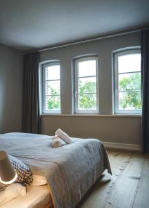 une chambre avec un lit avec trois fenêtres dans l'établissement Ferienhaus Forsthaus Stolpe, à Stolpe