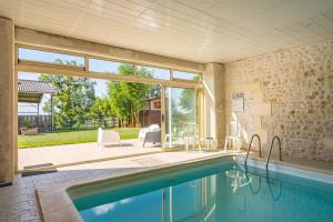 a swimming pool in a house with a large window at Gite Aix Piscine intérieure in La-Gripperie-Saint-Symphorien