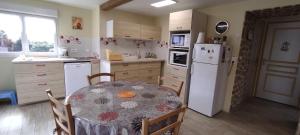eine Küche mit einem Tisch und einem weißen Kühlschrank in der Unterkunft Gîte Des Huttes in Bain-de-Bretagne + 35 Fotos