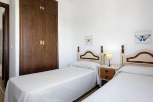 2 łóżka w pokoju z białymi ścianami i drewnianymi szafkami w obiekcie Alboran 208 w mieście Conil de la Frontera