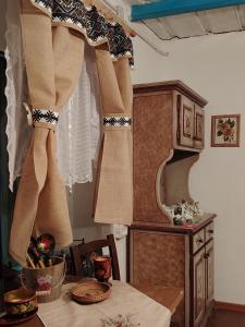 a kitchen with a table with a curtain on a window at Căsuța de chirpici in Dunavăţu de Sus +62 photos