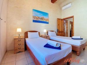 two beds in a room with two tables and a mirror at Gozo Farmhouse Escape with Rustic Charm & Pool in Sannat +49 photos