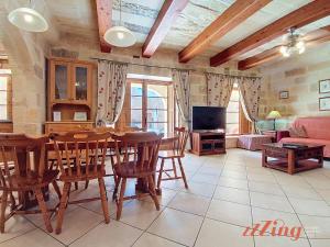 a living room with a table and chairs and a tv at Gozo Farmhouse Escape with Rustic Charm & Pool in Sannat