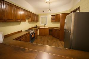 une cuisine avec des armoires en bois et un réfrigérateur en acier inoxydable dans l'établissement شاليه البرادايس 26 في درة العروس, à Durat Alarous 10 autres photos
