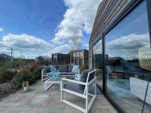 eine Terrasse mit einem Sofa und Stühlen auf dem Balkon in der Unterkunft Marina Strandbad Chalet Wellness Hideaway Haus Nr 402 in Olburgen