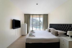 a bedroom with a large bed and a television at Salgados 4seasons Apartment in Albufeira