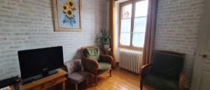 ein Wohnzimmer mit zwei Stühlen und einem Flachbildfernseher in der Unterkunft Ô Loue Rétro - 6 personne - 1er étage in Quingey