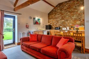ein Wohnzimmer mit einem roten Sofa und einer Küche in der Unterkunft Finest Retreats - Warren Cottage, Stowford in Little Torrington