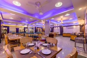a restaurant with wooden tables and chairs and purple lighting at The Arch Premium - Delhi IGI Airport in New Delhi