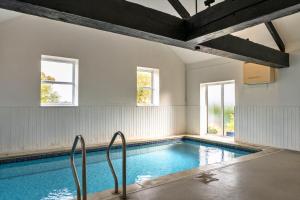 ein Hallenbad mit zwei Fenstern und einem Schwimmbad-Iterator in der Unterkunft Finest Retreats - Old Nog Cottage, Stowford in Little Torrington