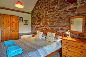 ein Schlafzimmer mit einem Bett und einer Ziegelwand in der Unterkunft Finest Retreats - Old Nog Cottage, Stowford in Little Torrington + 17 Fotos