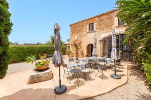 eine Terrasse mit Tischen, Stühlen und Sonnenschirmen in der Unterkunft El Palomar in Santanyi