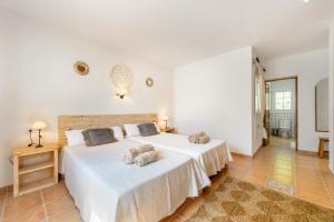 two beds in a room with white walls and tile floors at Casa Olivo in Sant Josep de Sa Talaia +26 photos