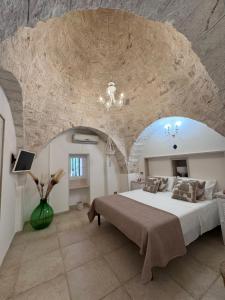 a bedroom with a large bed with a stone wall at I Tre Trulli in Locorotondo