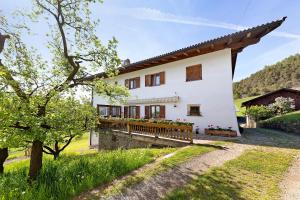 a large white house with a wooden porch at Moar im Rumsein - Apt Etschblick in San Genesio Atesino