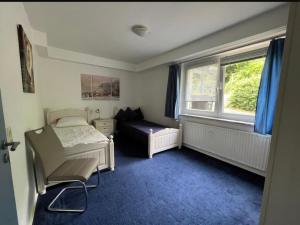 a bedroom with a bed and a chair and a window at Wohnung Blume in Niederdorla