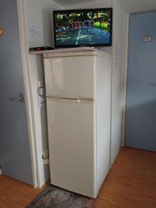 un réfrigérateur blanc avec une télévision dessus dans l'établissement Mobile home climatisé au Lac de Lougratte, à Lougratte