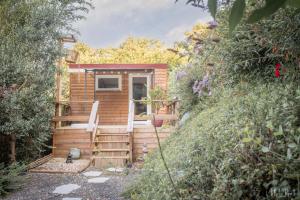 a tiny house with a porch and a door at La roulotte de Fichous in Fichous-Riumayou