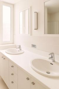 a white bathroom with two sinks and a mirror at Hyper Centre DEAUVILLE 3 chambres in Deauville +25 photos