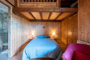 une chambre avec un lit dans une pièce aux murs en bois dans l'établissement L'Escampette à la Fontanette, à Saint-Pancrace
