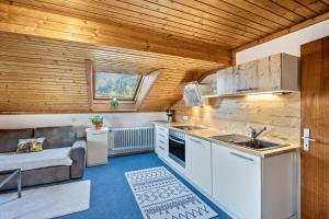 a kitchen with white cabinets and a couch in a room at Haus Bergliebe - Zugspitzblick in Pfronten