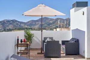een patio met een parasol, stoelen en een tafel bij Nerja Boutique B2 Street level in Nerja
