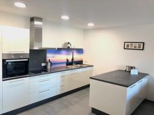 a kitchen with white cabinets and a black counter top at Ferienwohnung Bodensee in Schnerkingen