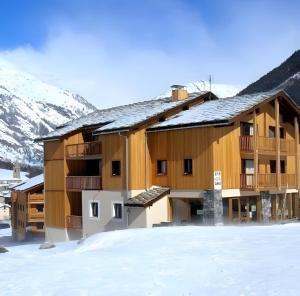 ein großes Holzgebäude im Schnee mit Bergen in der Unterkunft Au Refuge D'Hirka in Val Cenis
