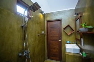 baño con ducha, lavabo y puerta en Kelly Ahangama, en Ahangama