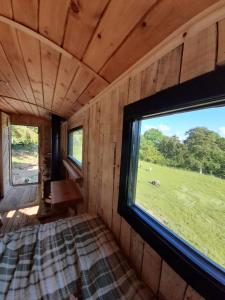 una habitación con una cama y una ventana grande en Sylvan Spaces, en Llanfyllin