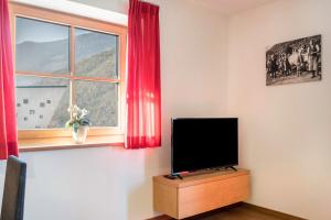 ein Flachbildfernseher auf einem Holzständer neben einem Fenster in der Unterkunft Apartments Gojer Vernatsch in Karneid
