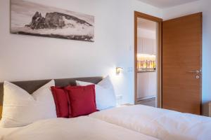 ein Schlafzimmer mit einem weißen Bett mit roten Kissen in der Unterkunft Apartments Gojer Vernatsch in Karneid