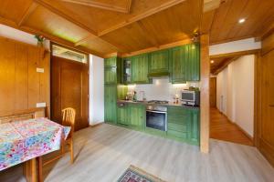 eine Küche mit grünen Schränken und einem Tisch in einem Zimmer in der Unterkunft Appartamento Michaela a Vinigo in Vinigo + 18 Fotos