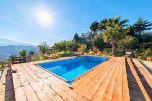 a swimming pool on a wooden deck next to a house at Vista Alcantara Mountain Wellness in Motta Camastra