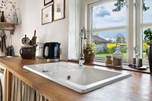 a white sink in a kitchen with a window at Pommernhuus an de Kark in Süderholz +13 photos