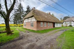 an old house with a thatched roof on a dirt road at Pommernhuus an de Kark in Süderholz