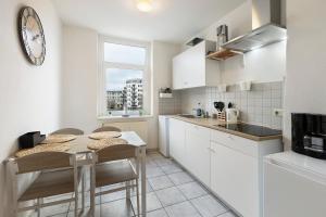 une cuisine avec une table et des chaises et une horloge au mur dans l'établissement Wohnen am Wissenschaftshafen, à Magdebourg