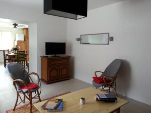 a living room with two chairs and a table and a television at Le gîte de Gemma in Montain
