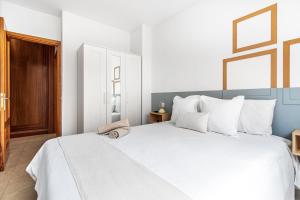 ラスパルマス・デ・グランカナリアにあるCasa Almi Las Palmasの白い枕が付いた大きな白いベッドのある寝室