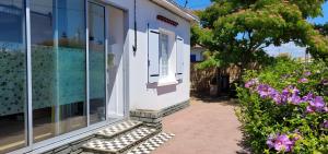 a porch of a house with a window and flowers at Maison La Guitoune Fautaise in L'Aiguillon-la-Presqu'île
