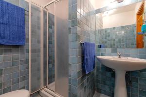 y baño de azulejos azules con lavabo y ducha. en Casa Claudia Le Tonnare Stintino, en Stintino 20 fotos más