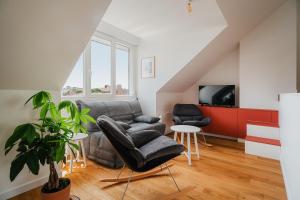 a living room with a couch and chairs and a tv at Logement calme proche centre ville in Rennes