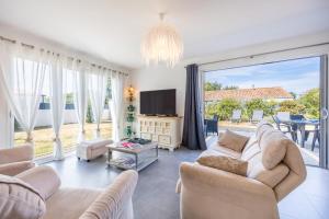 a living room with a couch and a tv and a large window at La Maison du Payré - proche plages in Talmont-Saint-Hilaire